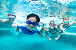Underwater view of children diving into water