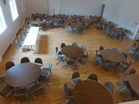 room with wooden floor set up with round tables and chairs