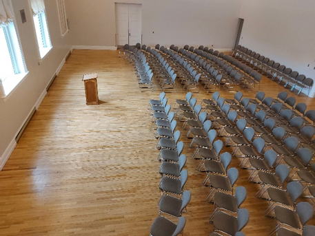 room with wooden floors and chairs in rows facing a podium