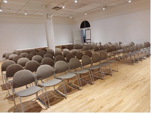 white walled room with pale wooden floors and grey chairs set in rows