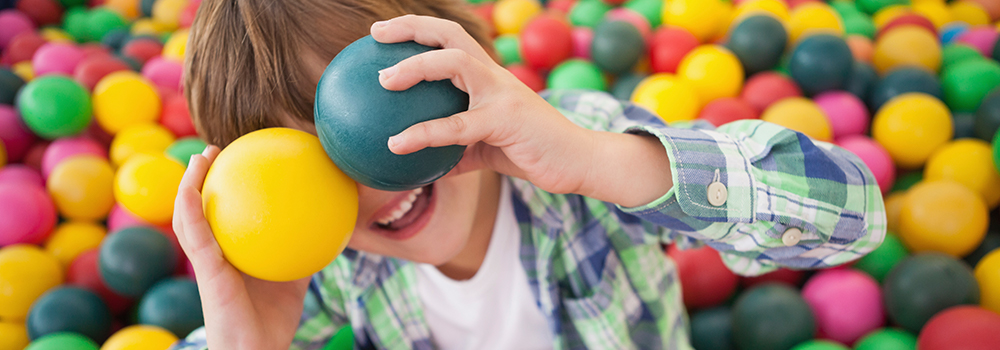 Child playing with multi-coloured balls, pretending two are eyes