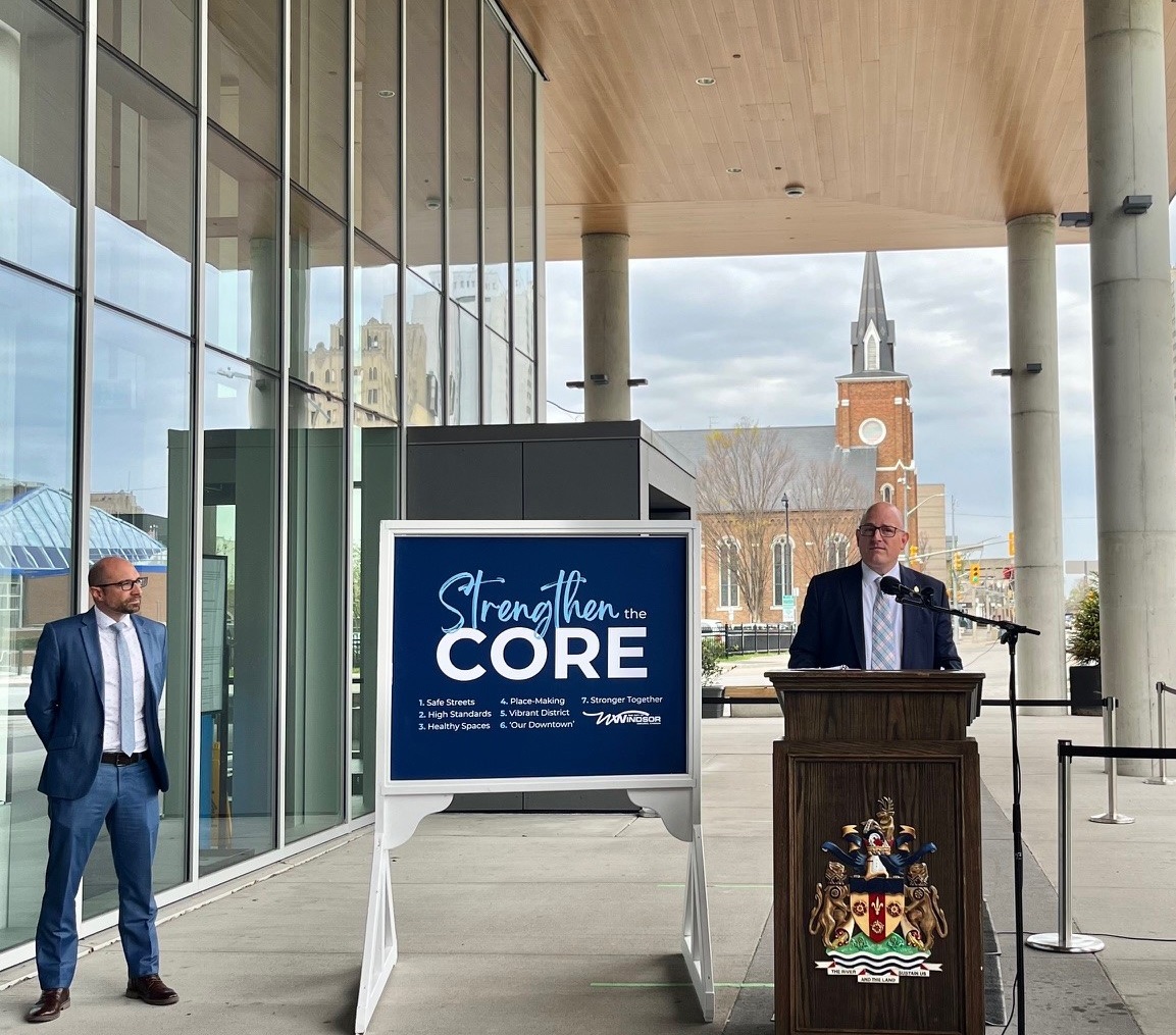 Mayor Dilkens at a podium and Commissioner of Human and Health Services Andrew Daher flanking a sign that reads, Strengthen the Core, 1, Safe Streets; 2, High Standards; 3, Healthy Spaces; 4, Place-Making; 5, Vibrant District; 6, Our Downtown; 7, Stronger Together